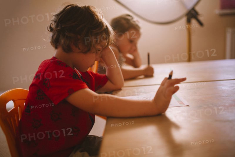 Caucasian boy and girl sitting at table with pencil and paper