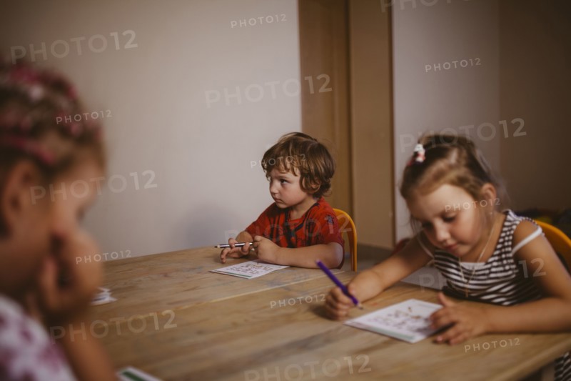 Caucasian boy and girl sitting at table coloring