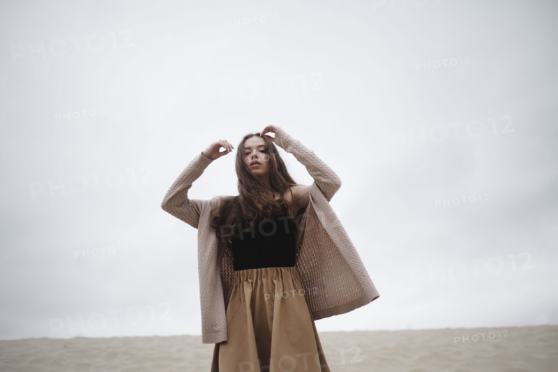 Caucasian woman standing with arms raised at beach