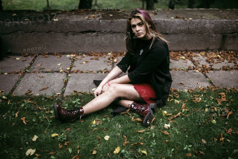 Serious Caucasian woman sitting in autumn leaves