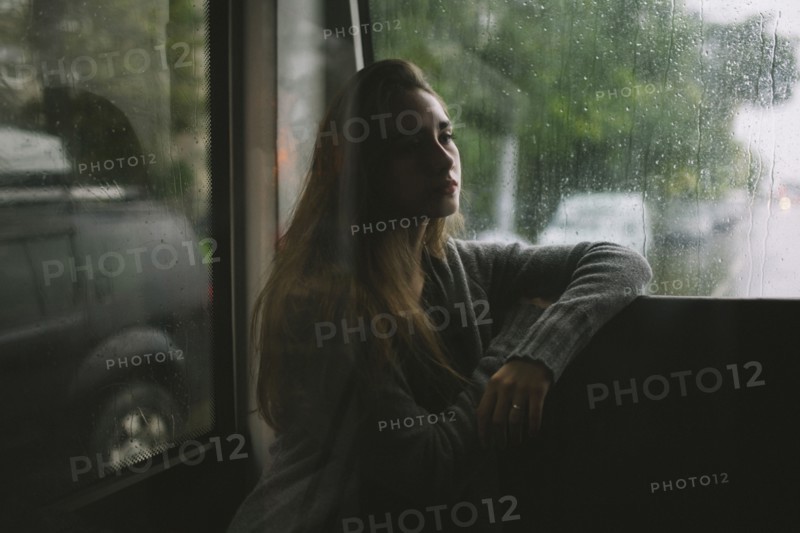 Pensive Caucasian woman sitting on bus in rain