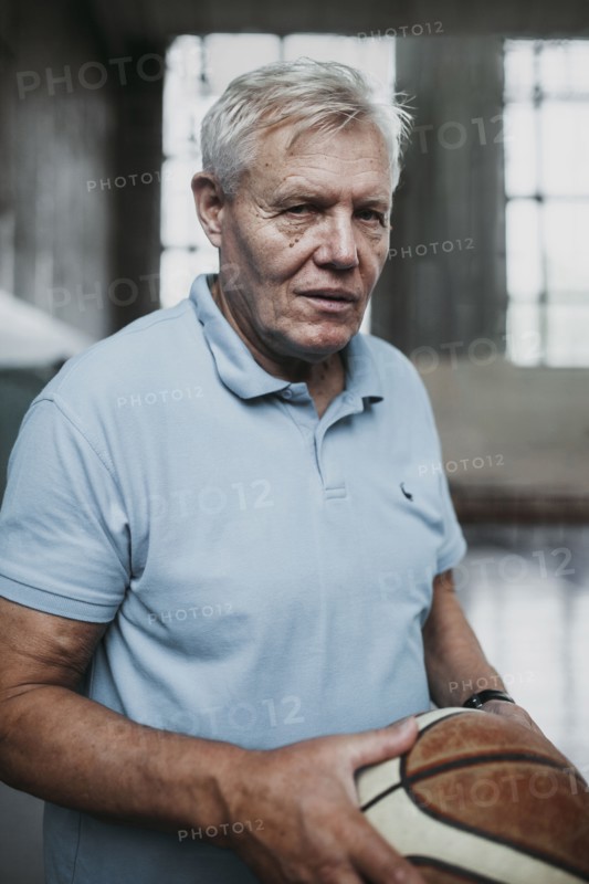Portrait of serious Caucasian man holding basketball in gymnasium