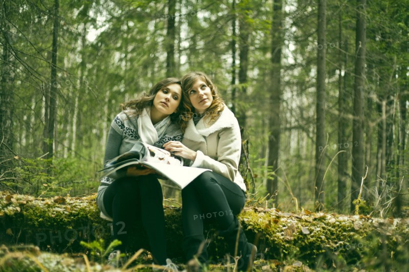 Caucasian women reading magazine in forest