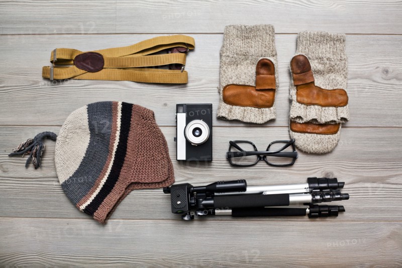 Photographer's equipment and clothing items arranged on floor