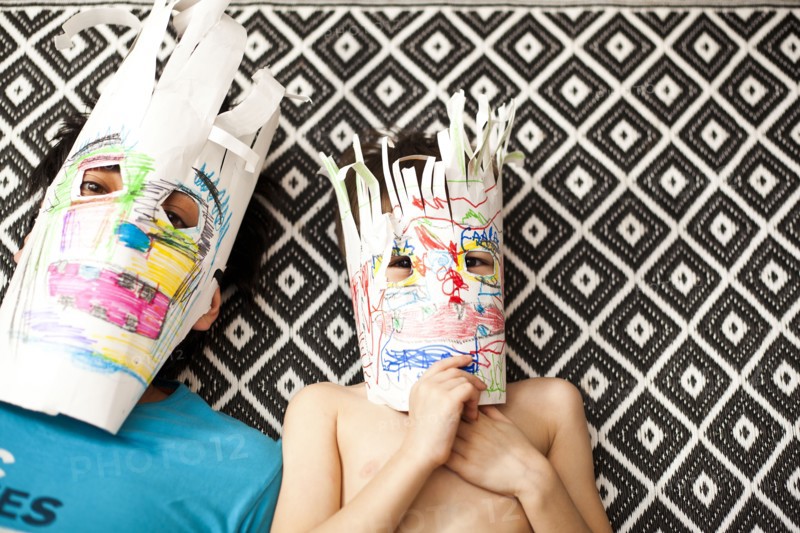 Father and son wearing colorful masks on carpet