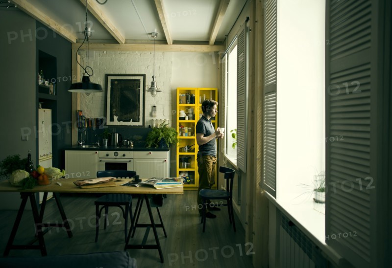 Caucasian man looking out kitchen window