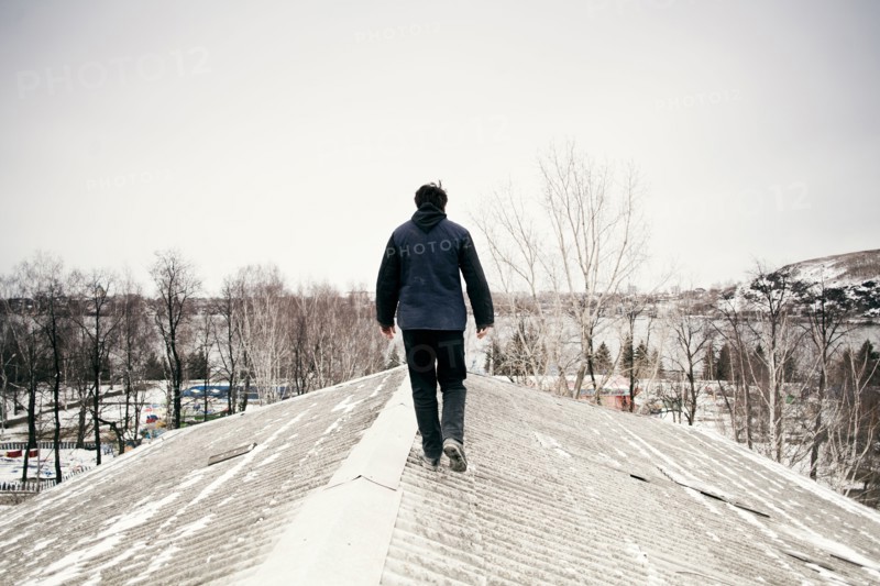 Caucasian man walking on snowy roof