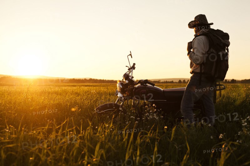 Mari man standing in field with motorcycle