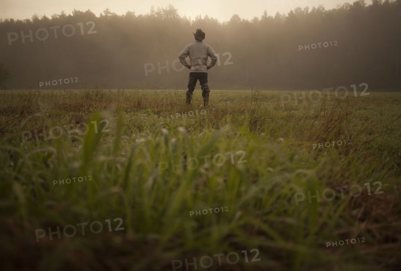 Mixed race man standing in field in rural landscape