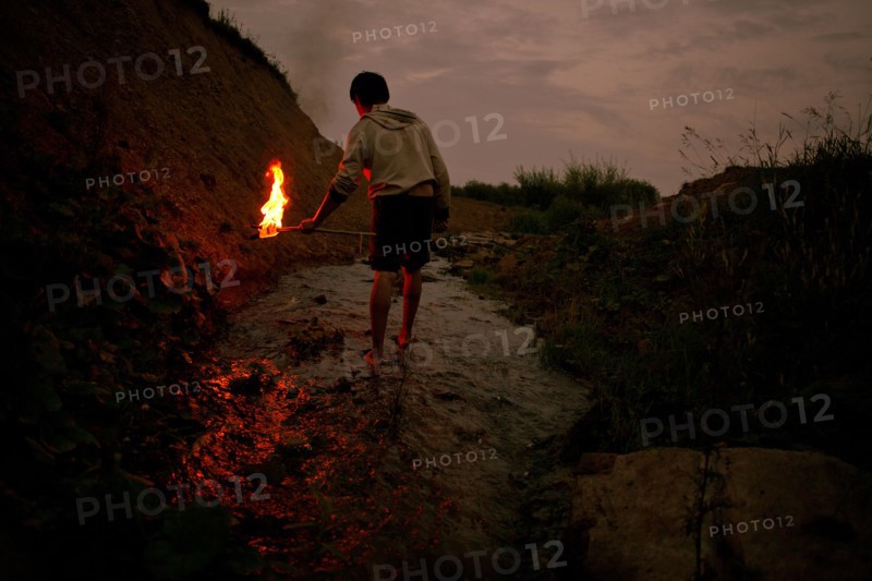 Mari man holding torch in rural creek