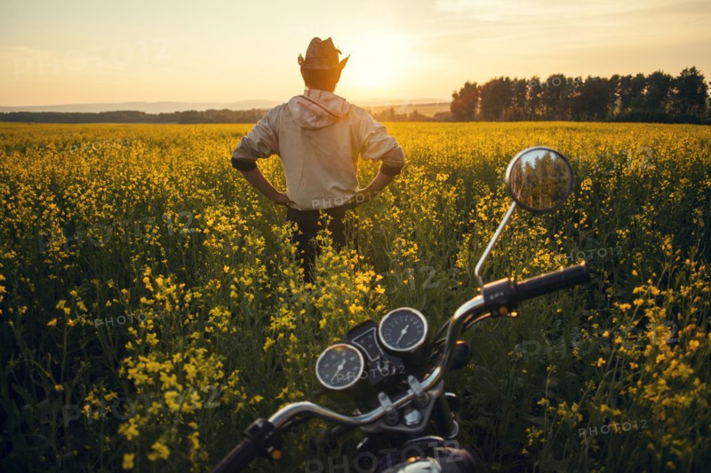 Mari man standing near motorcycle in field of flowers