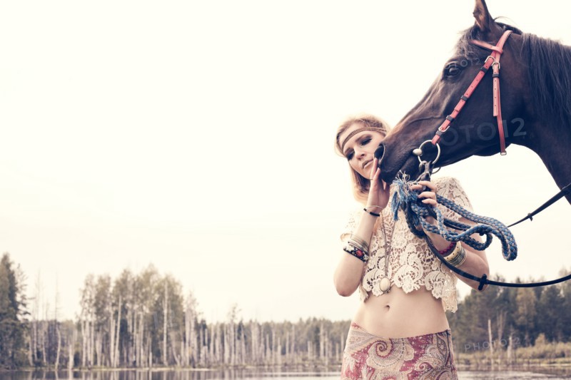 Caucasian woman petting horse near lake