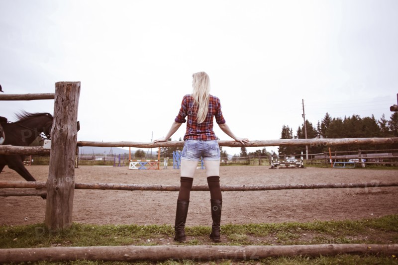 Caucasian woman watching horses on ranch