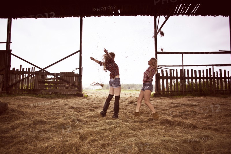 Caucasian women playing in hay in barn