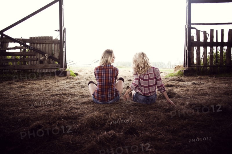 Caucasian women sitting on hay in barn