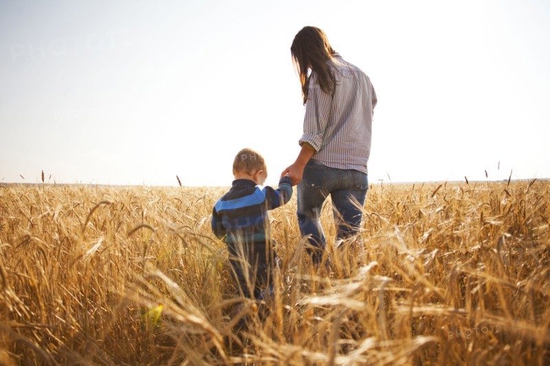 Caucasian mother and son walking in rural field