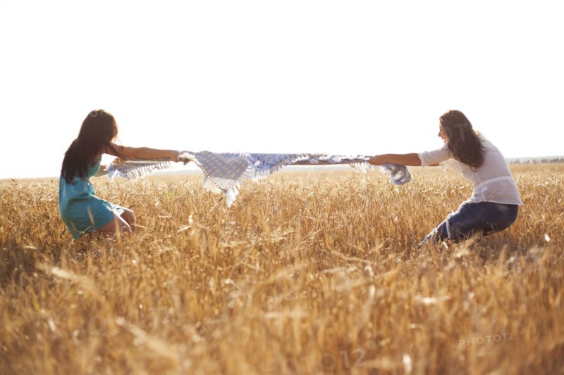 Caucasian women playing tug-of-war in rural field