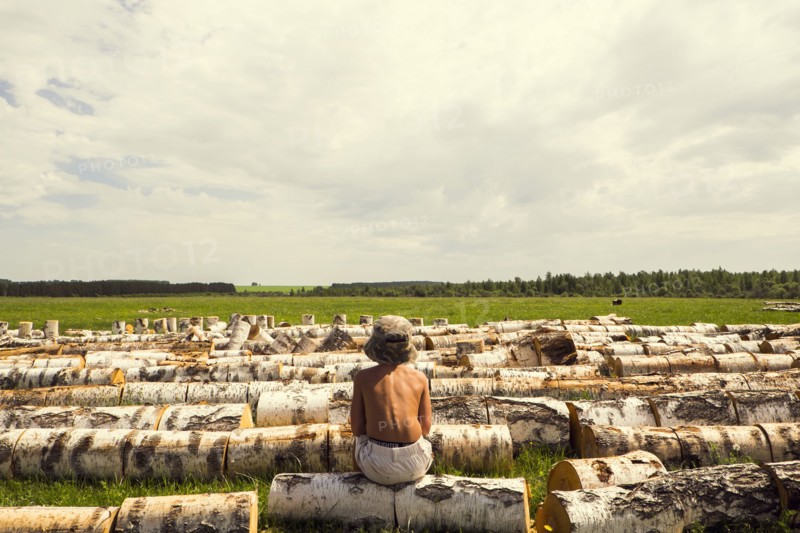 Mari boy sitting on log in rural field