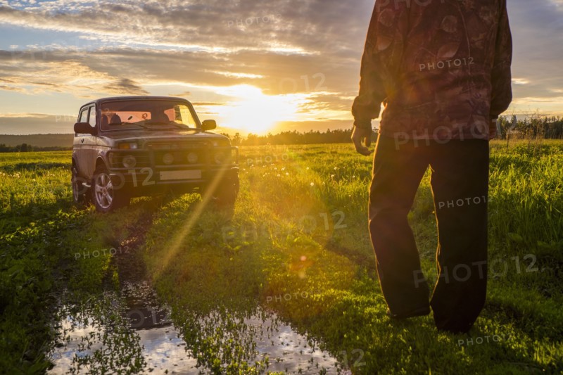 Mari man walking toward car at sunset in rural field