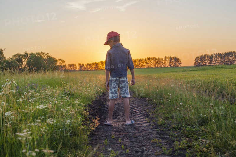 Mari boy standing in tire tracks in rural field