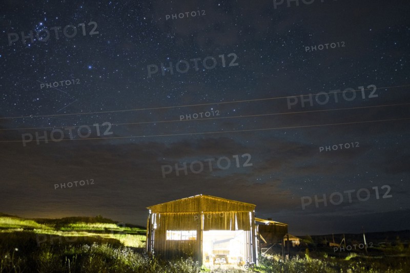 Illuminated cabin under starry night sky