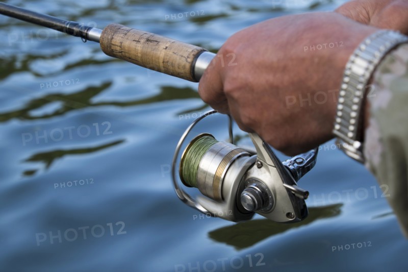 Hands of Mari man holding fishing rod in river