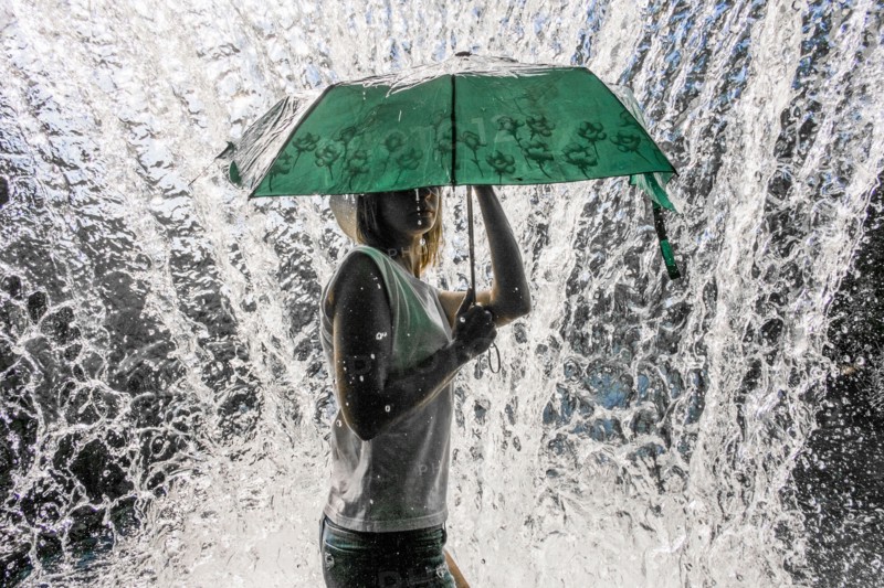 Caucasian woman holding umbrella near splashing water