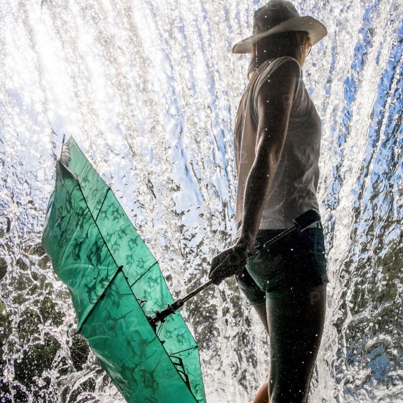 Caucasian woman holding umbrella near splashing water