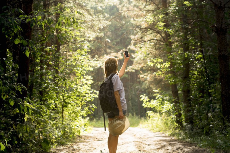 Caucasian woman photographing forest trees with cell phone