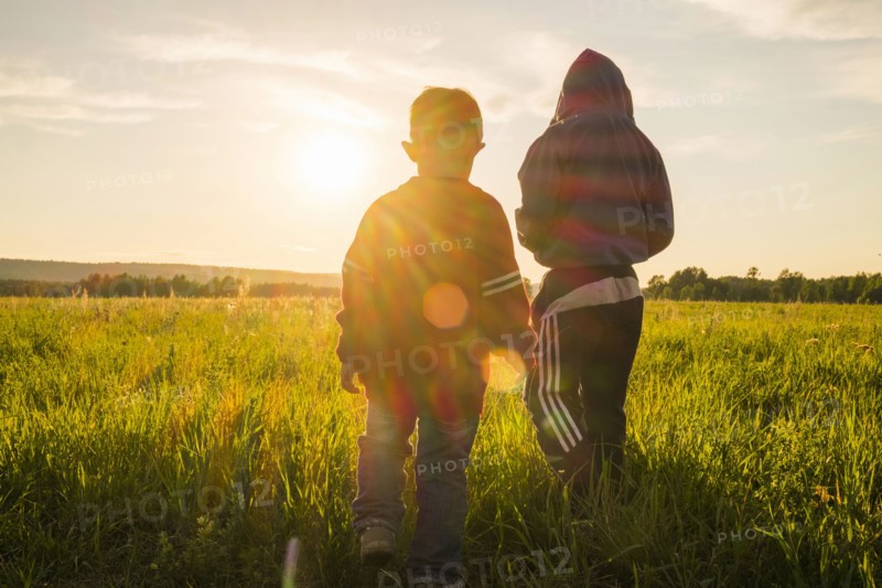 Mari boys walking in field at sunset