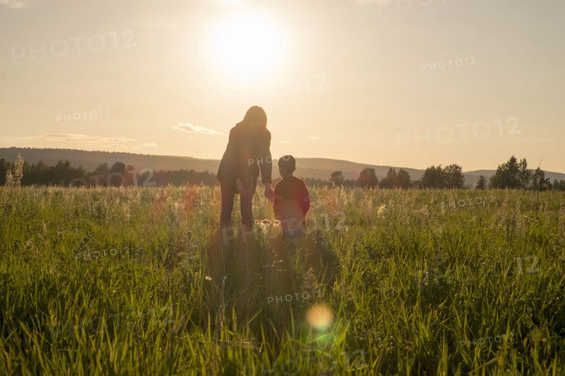 Woman and son standing in field at sunset