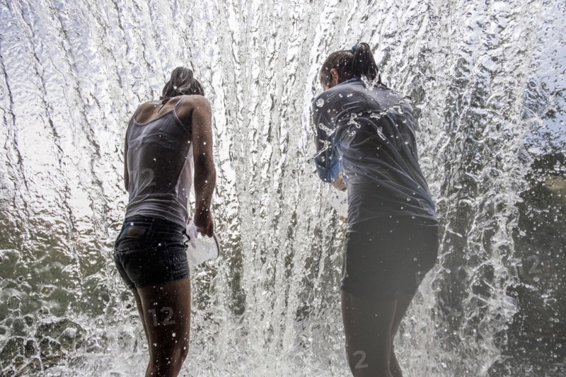 Caucasian mother and daughter standing in waterfall