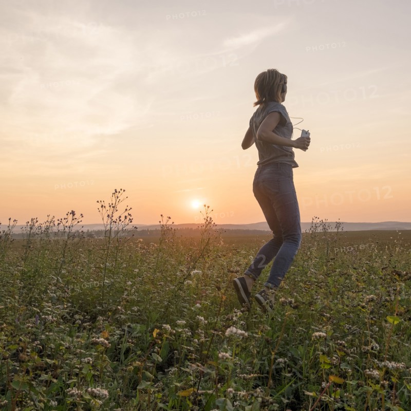 Caucasian woman dancing in field at sunset