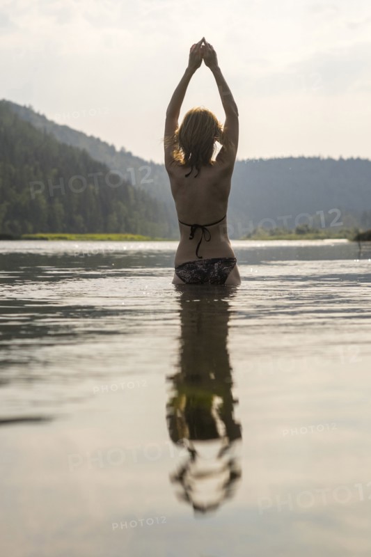 Caucasian woman standing in lake wearing bikini