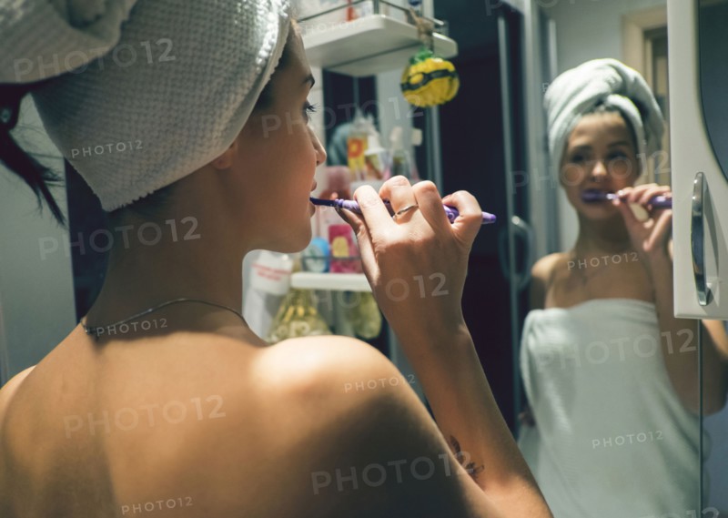 Caucasian woman brushing teeth in mirror