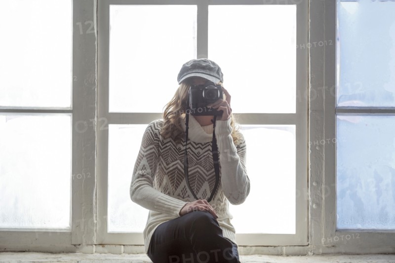 Caucasian woman on window sill photographing with camera
