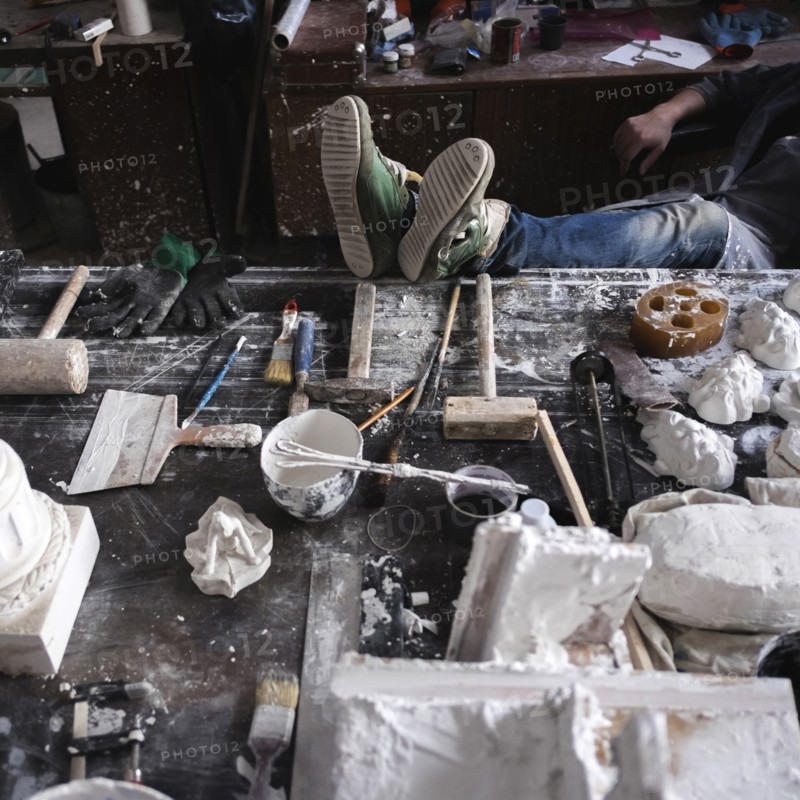 Feet of Caucasian sculptor on table