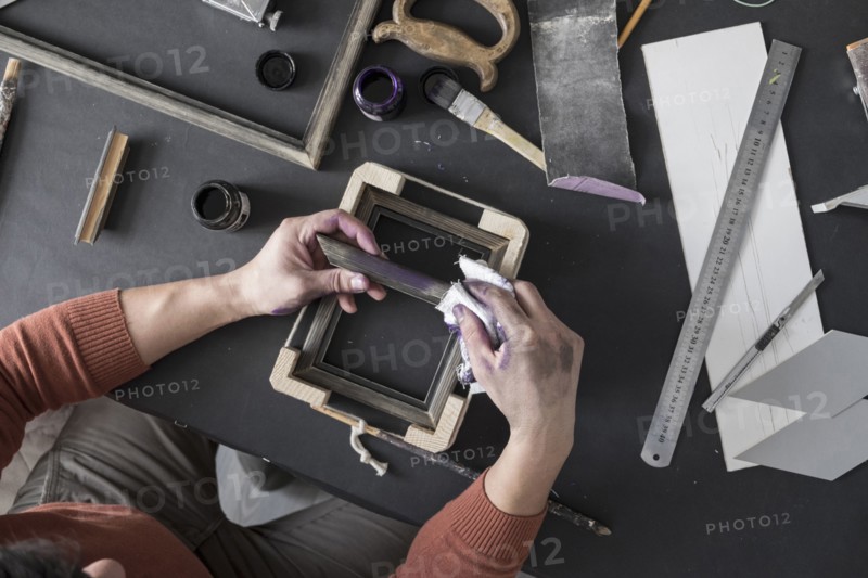 Hands of Caucasian artist staining picture frame