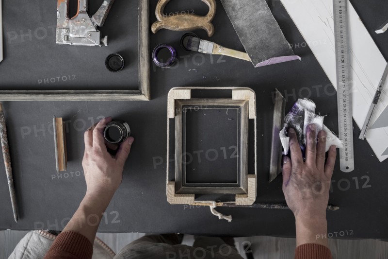 Hands of Caucasian artist staining picture frame