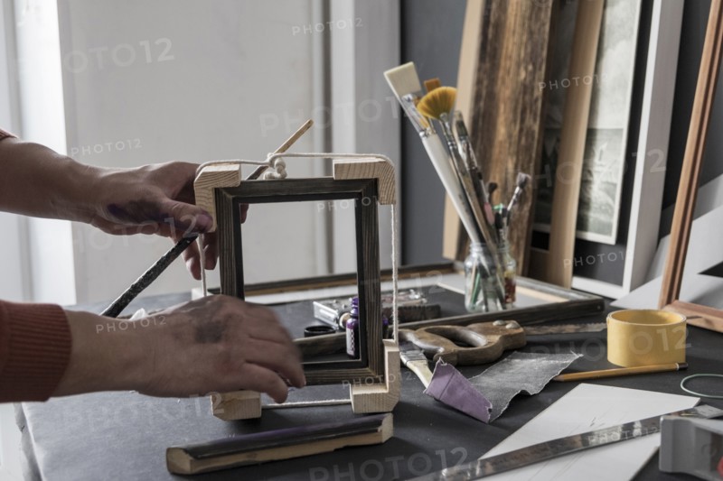 Hands of Caucasian artist making picture frame