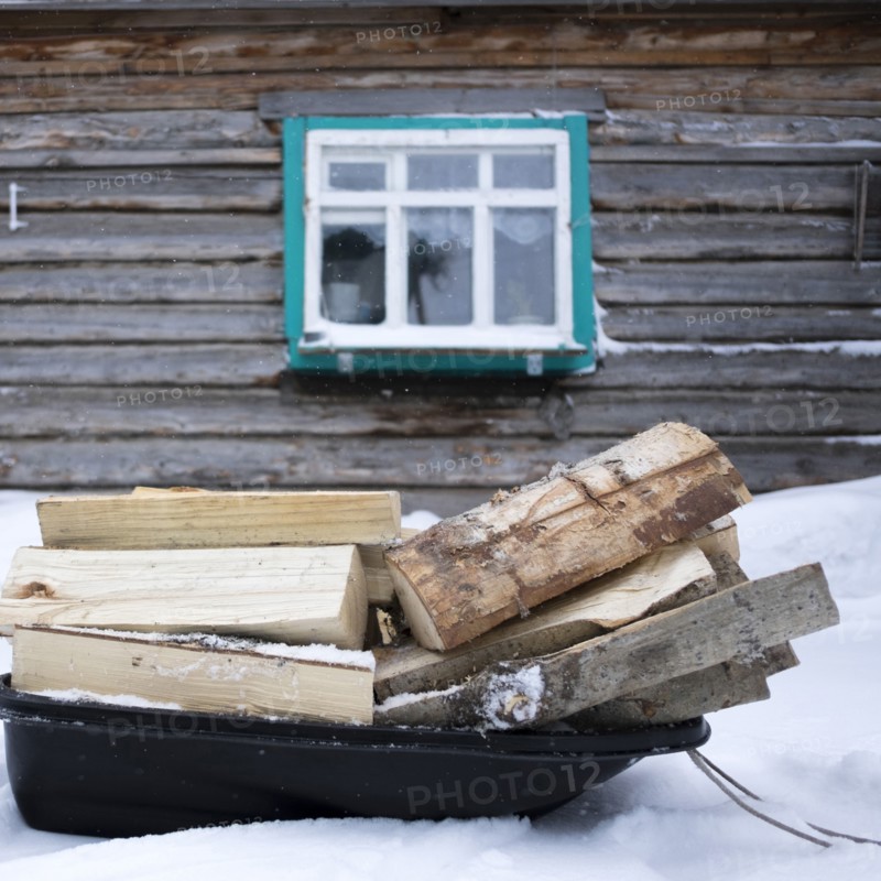 Firewood on sled in snow outside cabin