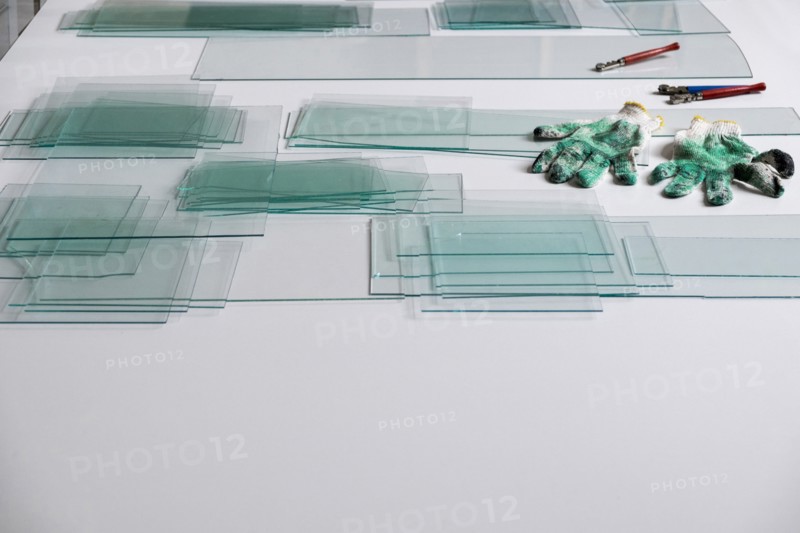 Piles of glass and glass cutter on white table