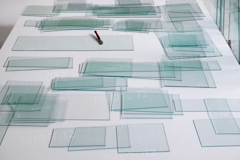 Piles of glass and glass cutter on white table
