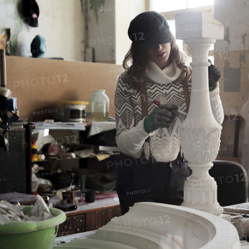 Caucasian artist sculpting with tool