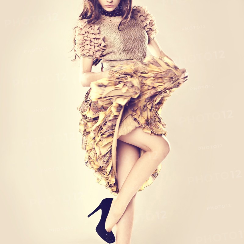 Caucasian woman wearing ruffled skirt standing on one leg