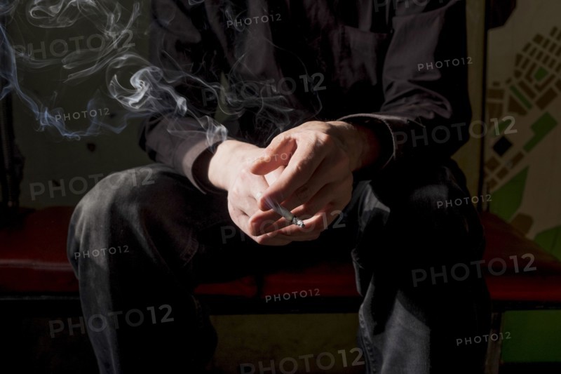 Midsection of Caucasian man smoking cigarette
