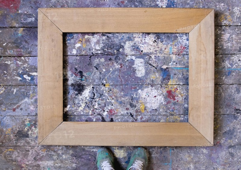 Feet standing over picture frame on wooden floor