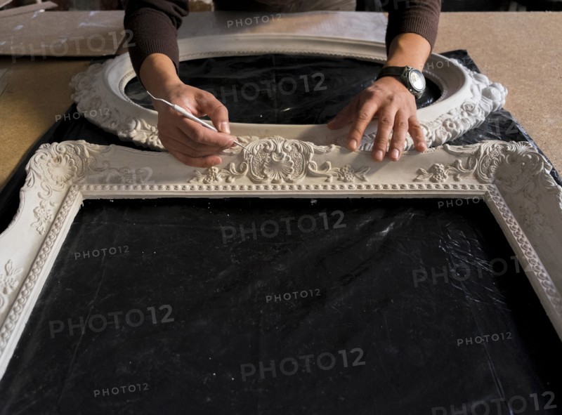 Hands of Caucasian man detailing picture frame