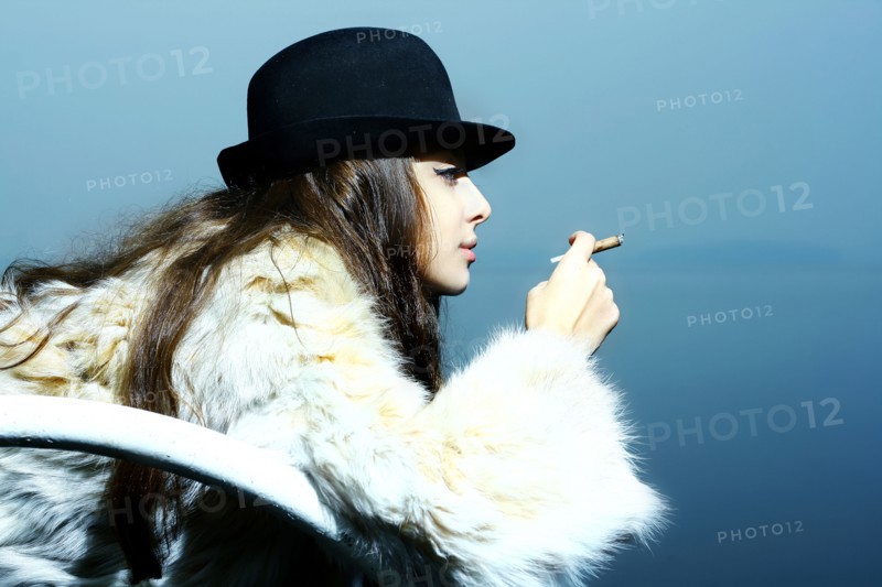 Portrait of glamorous woman wearing fur coat smoking cigarette
