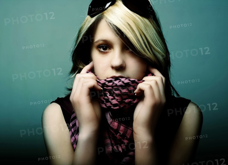 Portrait of serious Caucasian teenage girl holding scarf over mouth